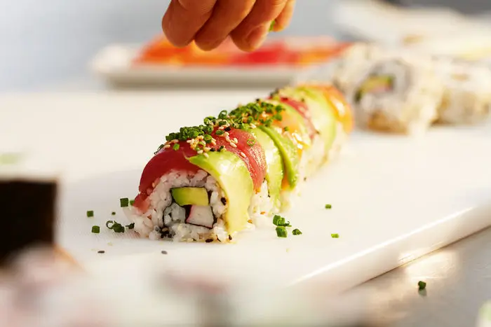Un plato de sushi elegantemente servido, visto desde arriba, sobre una pizarra oscura.